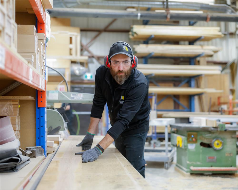 Employé d’un fournisseur local de finition intérieure travaillant le bois en atelier, illustrant l’expertise en portes intérieures et en finition intérieure au Québec.